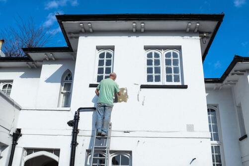 image of a man painting the exterior of a house